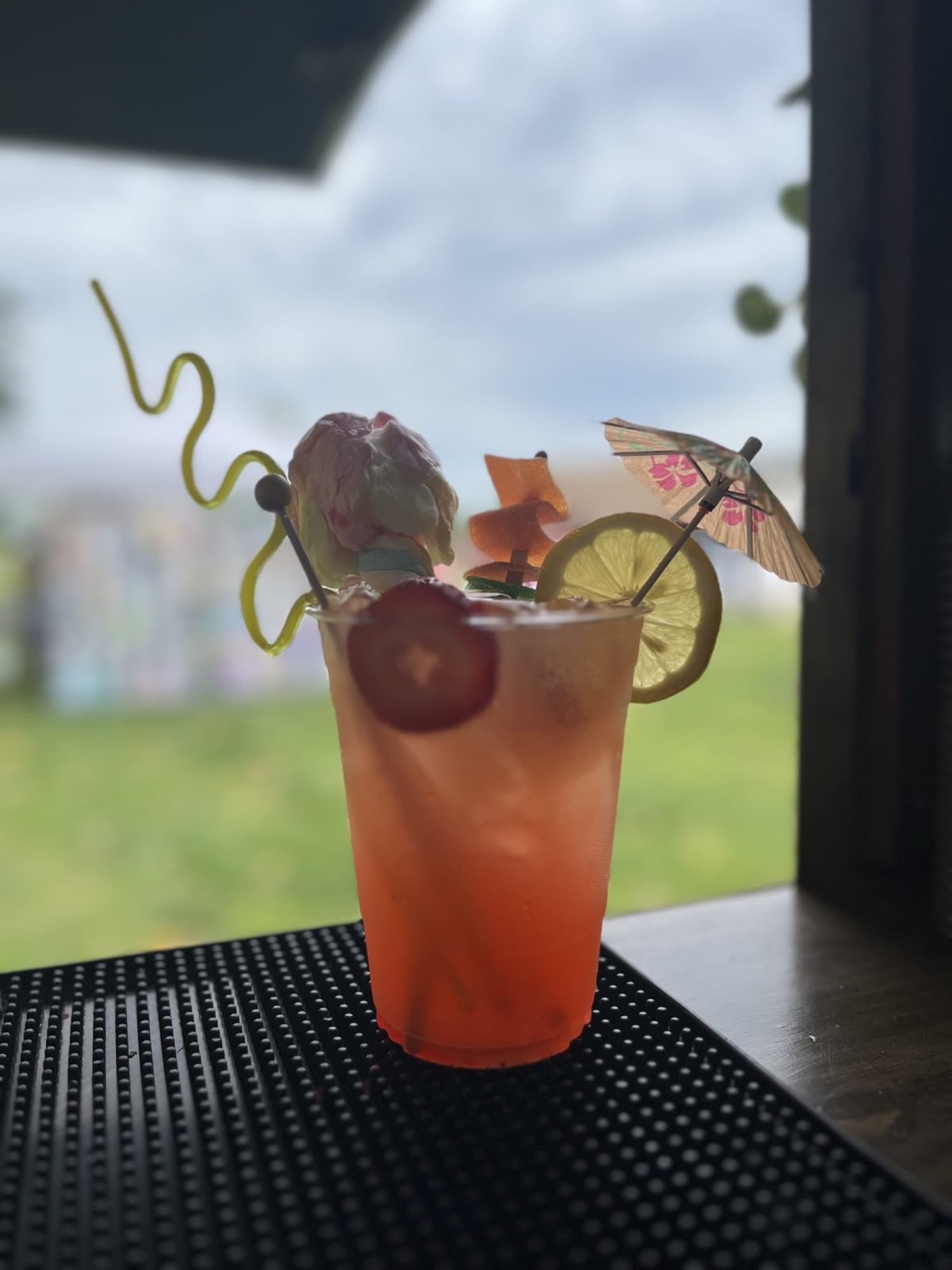 A pink signature cocktail with a paper umbrella, a strawberry and a lime wheel on the bar of The Blair.