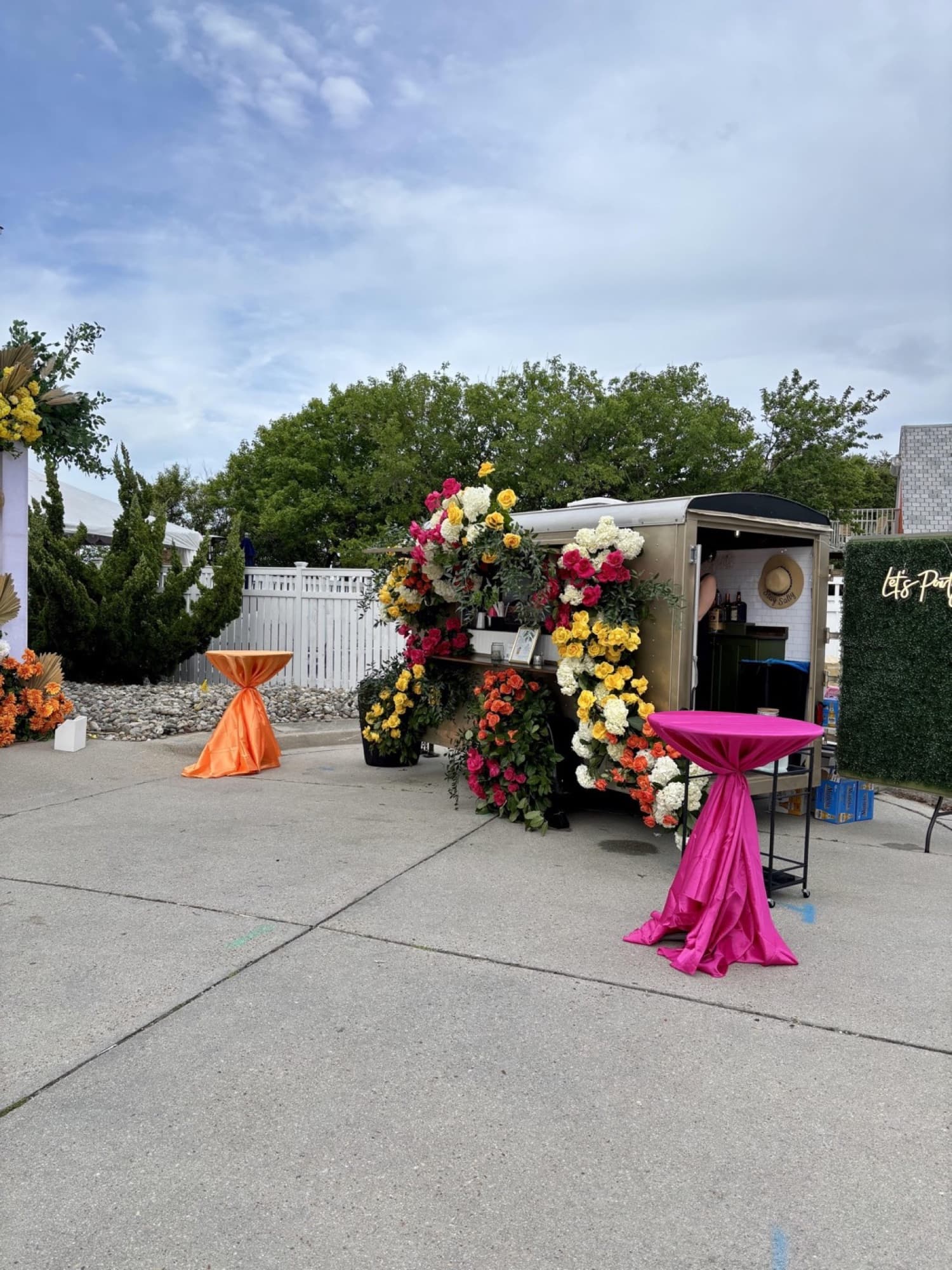 The flower-covered Blair with pink and orange draped cocktail tables before a coastal wedding reception.